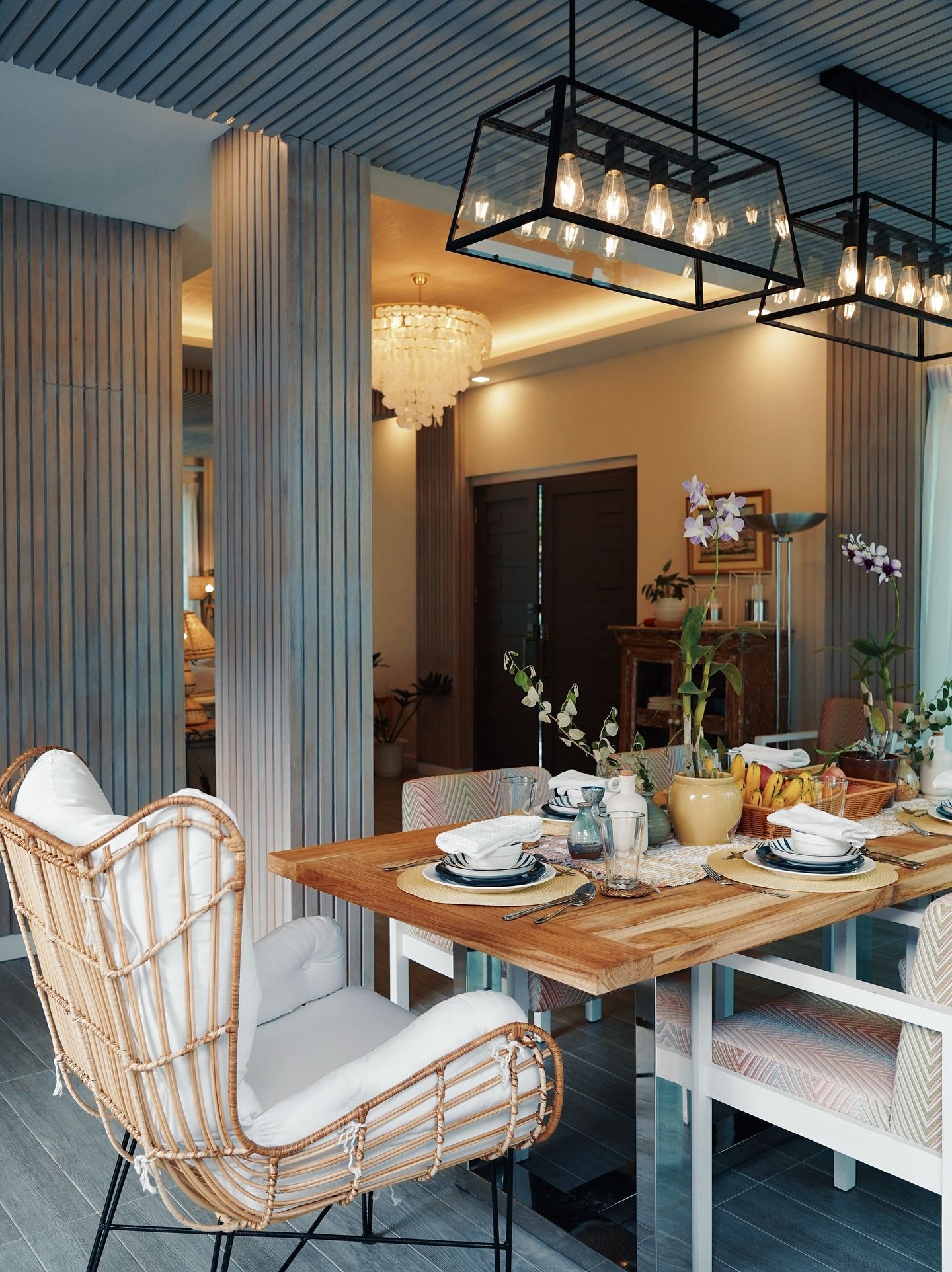 Dining room with a wooden table, woven chairs, and modern light fixtures.
