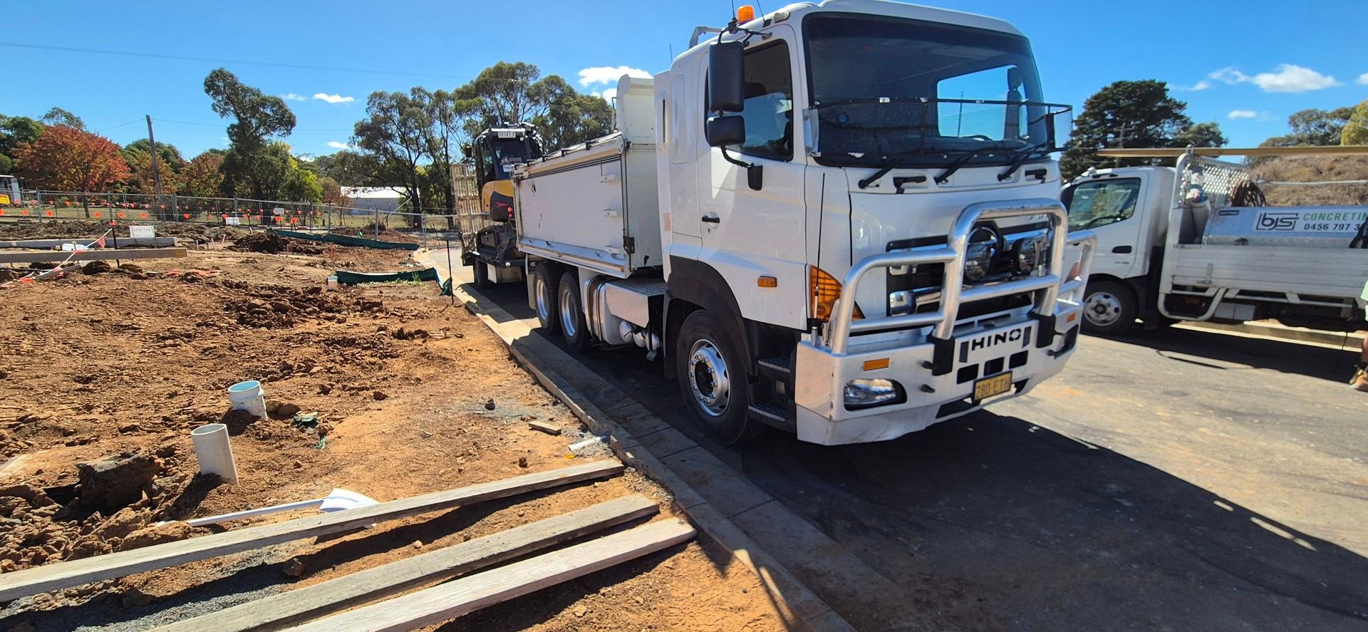 A white truck is parked on the side of the road next to a dirt field.