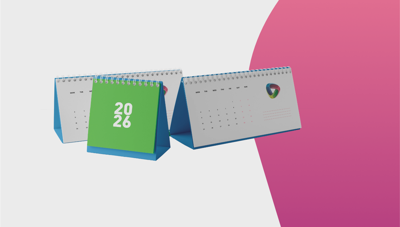 Three desk calendars for 2026, one green, two white, on a pink and white background.
