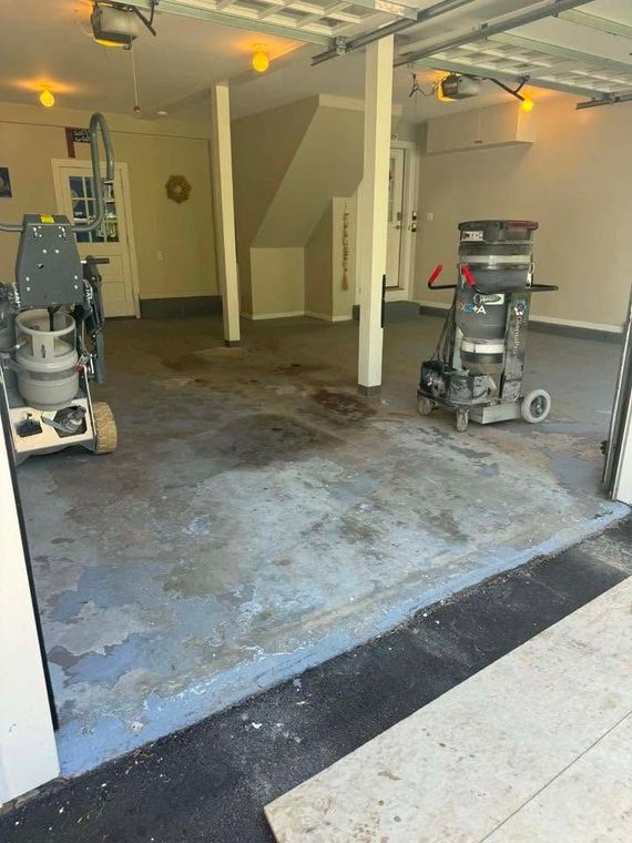 Person smoothing gray sealant on a floor with a trowel; indoor setting.