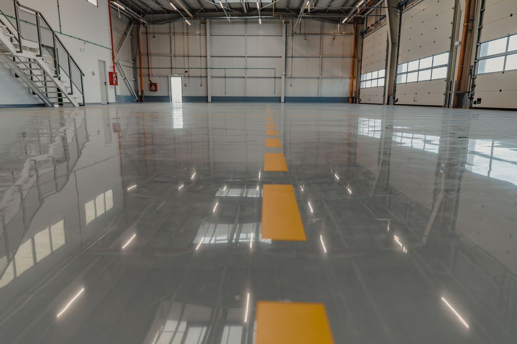 Shiny gray industrial floor with yellow stripe, open hangar interior, overhead lights.