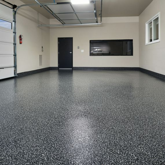 Empty garage with epoxy floor, black door, and a small window.