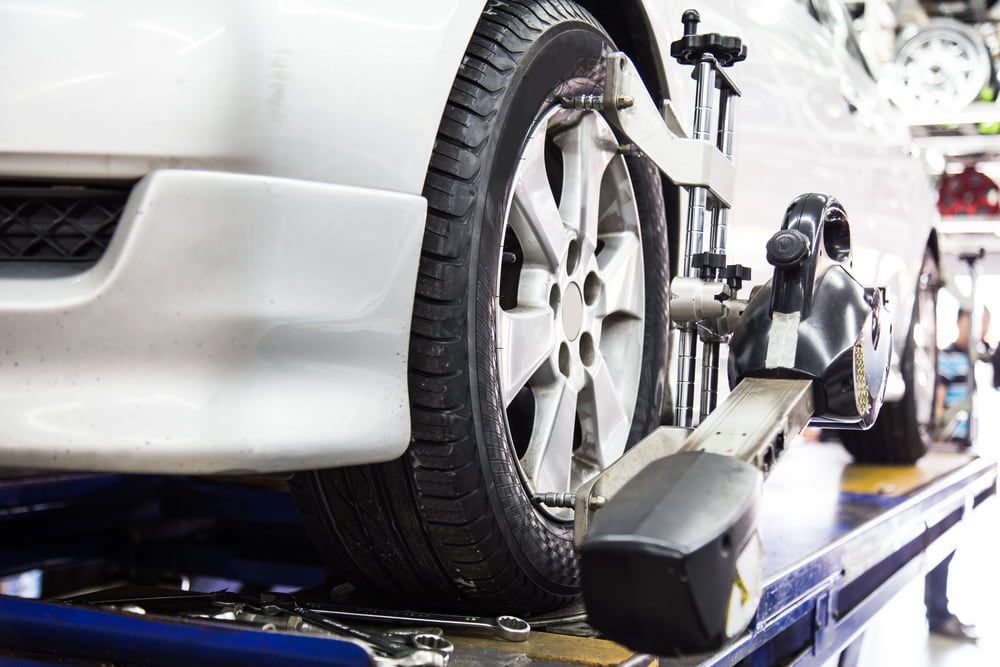 A White Car on a Mechanical Lift in a Garage — Berkeley Vale Tyre & Mechanical in Fountaindale, NSW