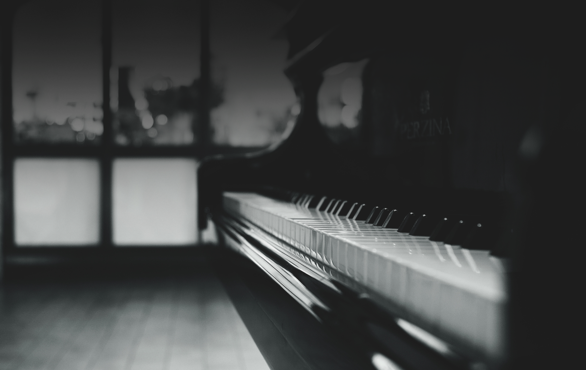 A black and white photo of a piano in a dark room.