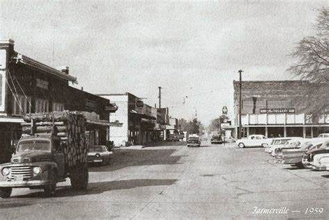 A vintage black-and-white street scene of Jayess, Mississippi, in 1948, featuring a logging truck and parked cars.
