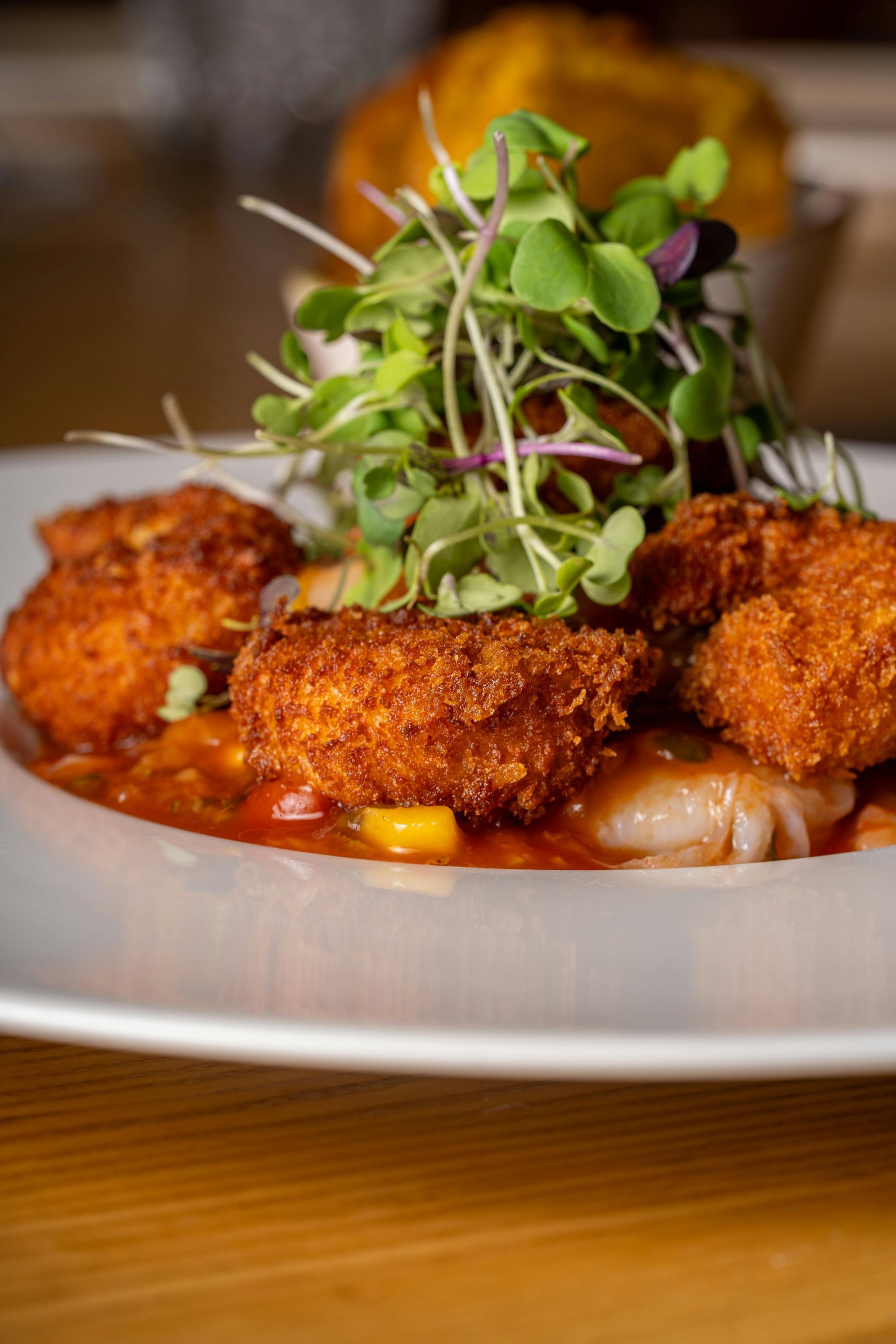 A plate of food with french fries , shrimp , fish , and dips on a table.