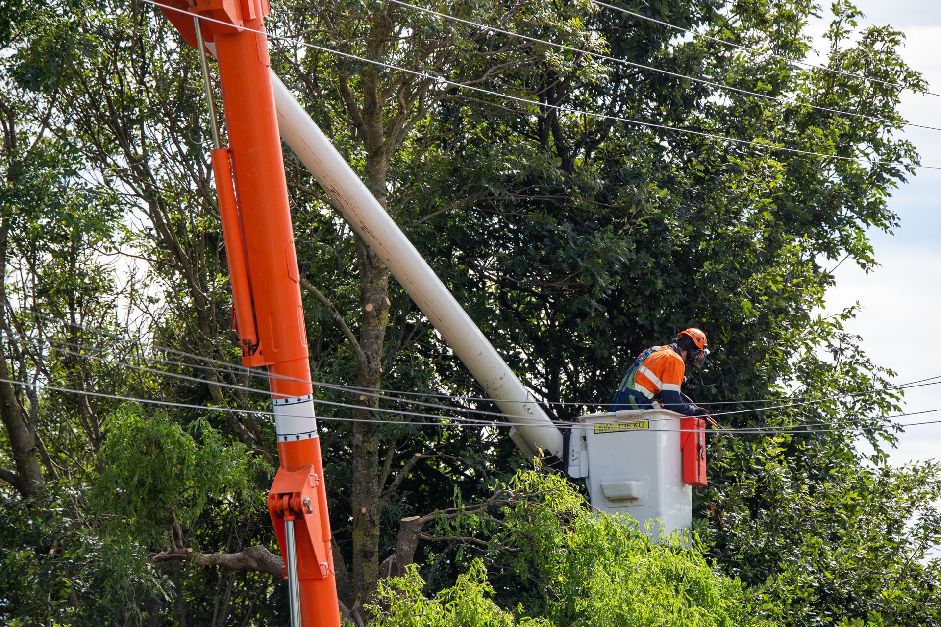 A Man in a Bucket is Working on a Power Line