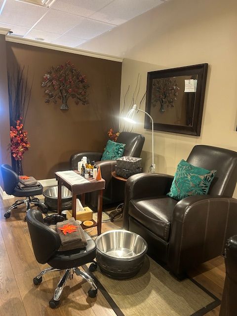 Pedicure station in a salon with two leather chairs, a foot bath, and decorative wall art.