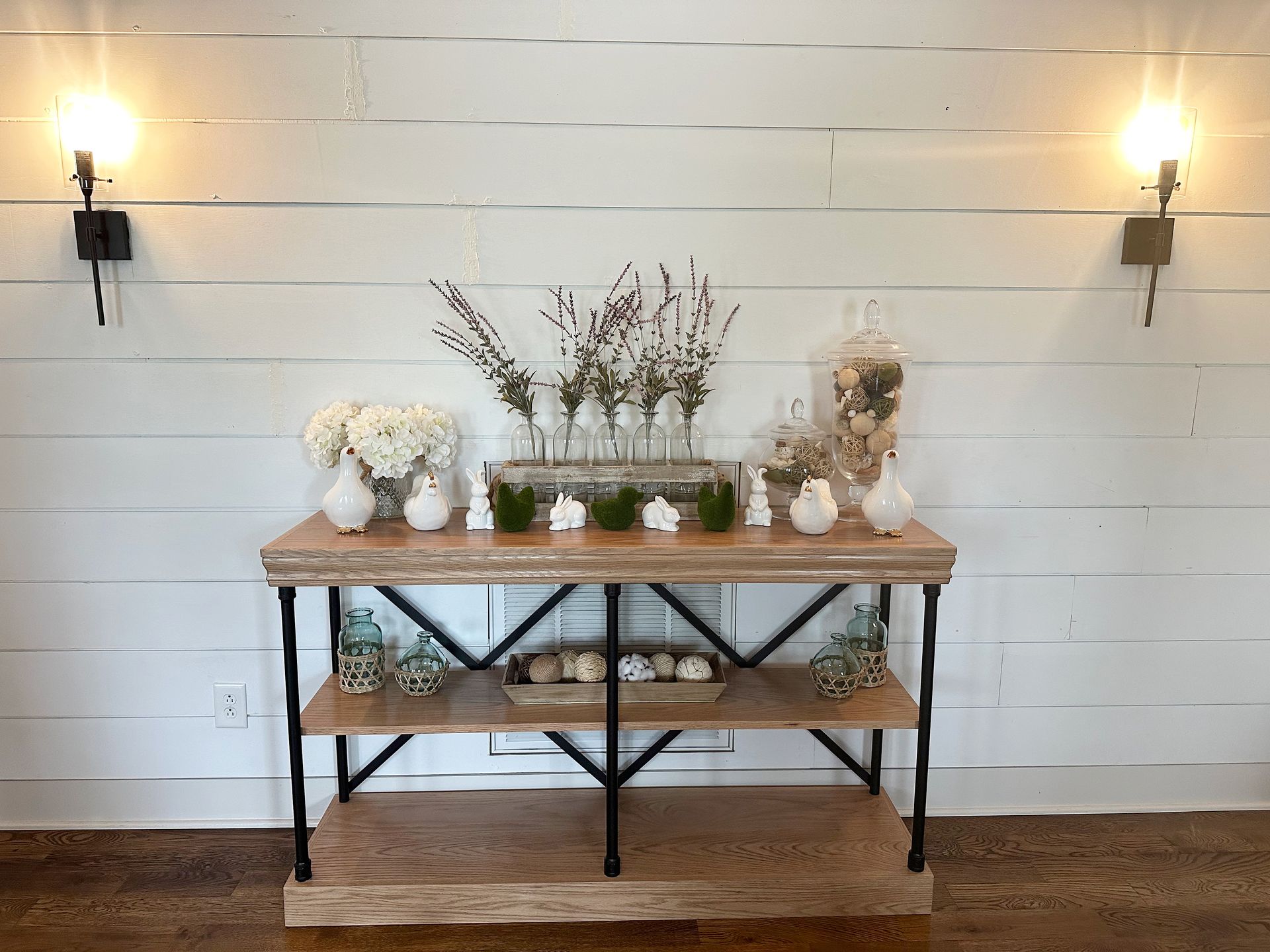 A wooden table with flowers and vases on it in a room.