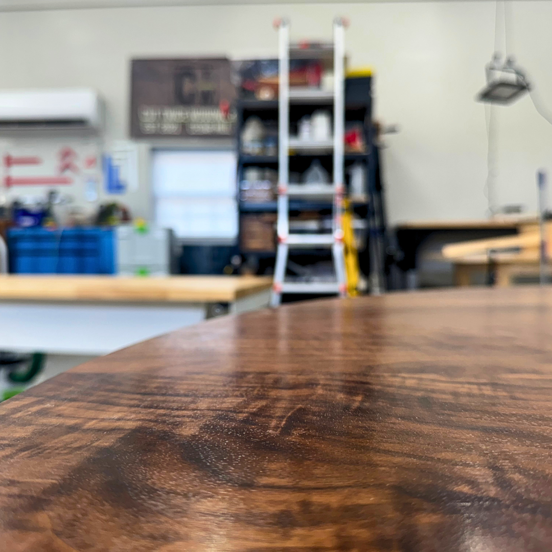 A wooden table in a workshop with a ladder in the background.