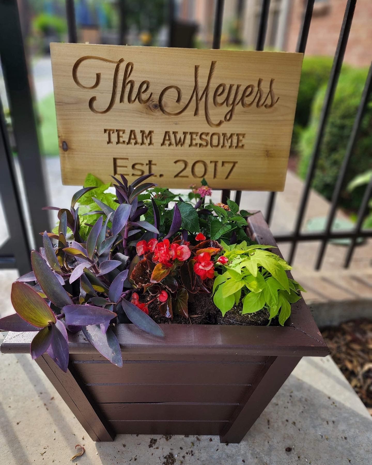 A wooden planter with flowers and a sign that says `` the meyers team awesome est . 2017 ''