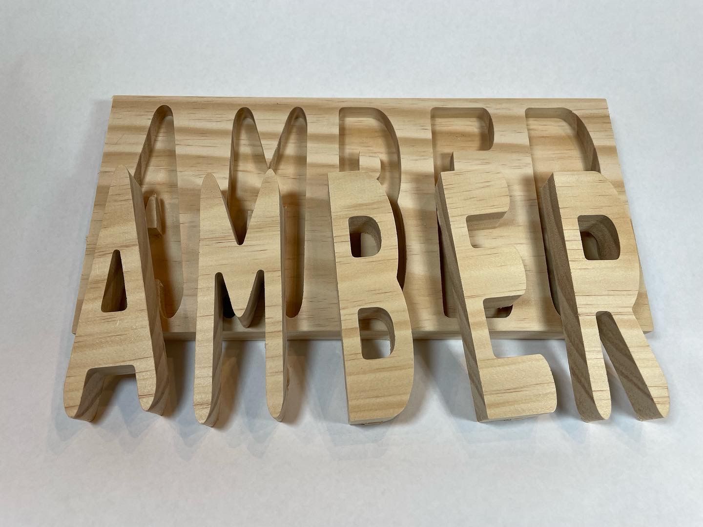 The word amber is cut out of wood on a white surface