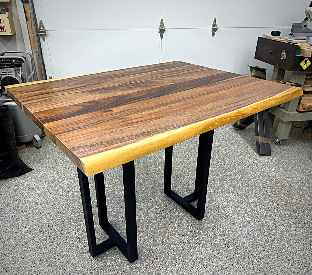 A wooden table with metal legs is sitting in a garage.