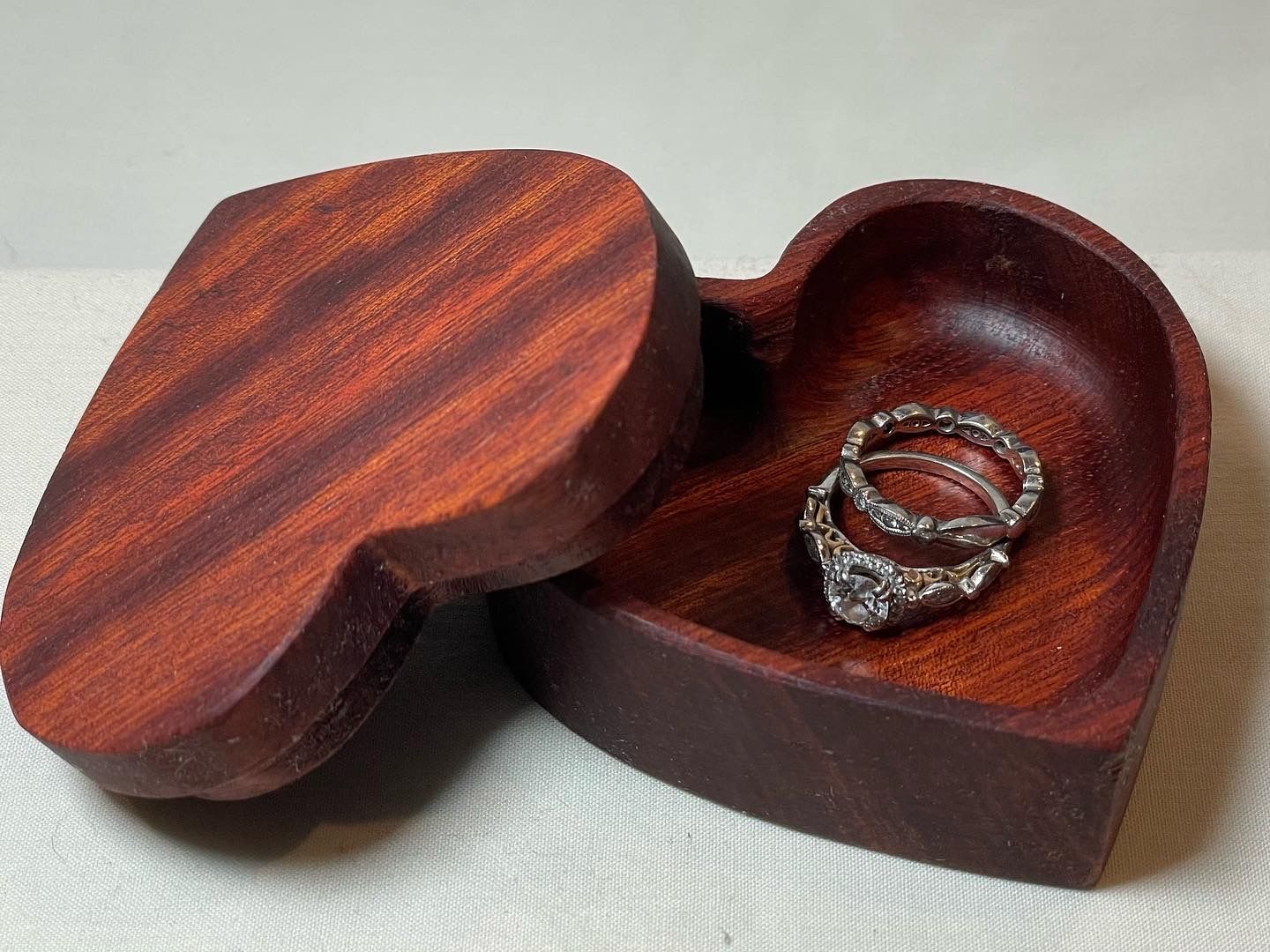 Two rings are in a heart shaped wooden box.