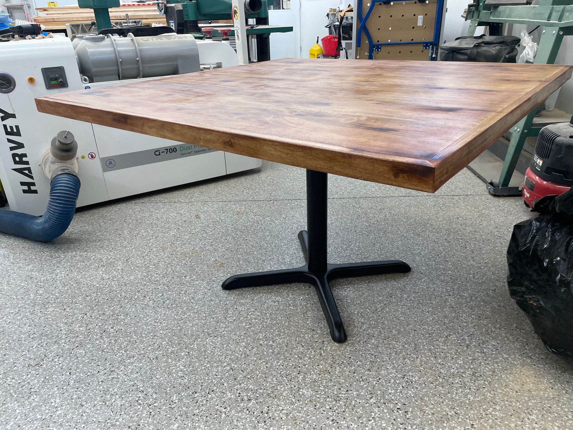 A wooden table is sitting in a garage next to a machine.