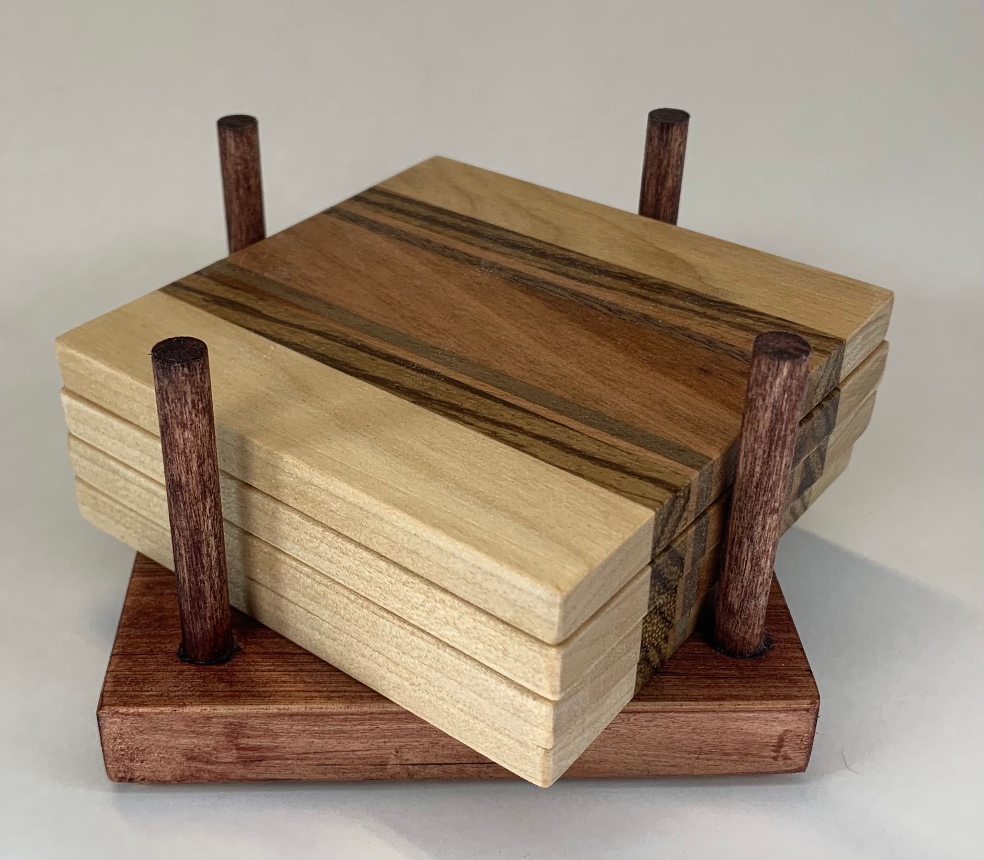 Four wooden coasters are stacked on top of each other on a wooden stand.