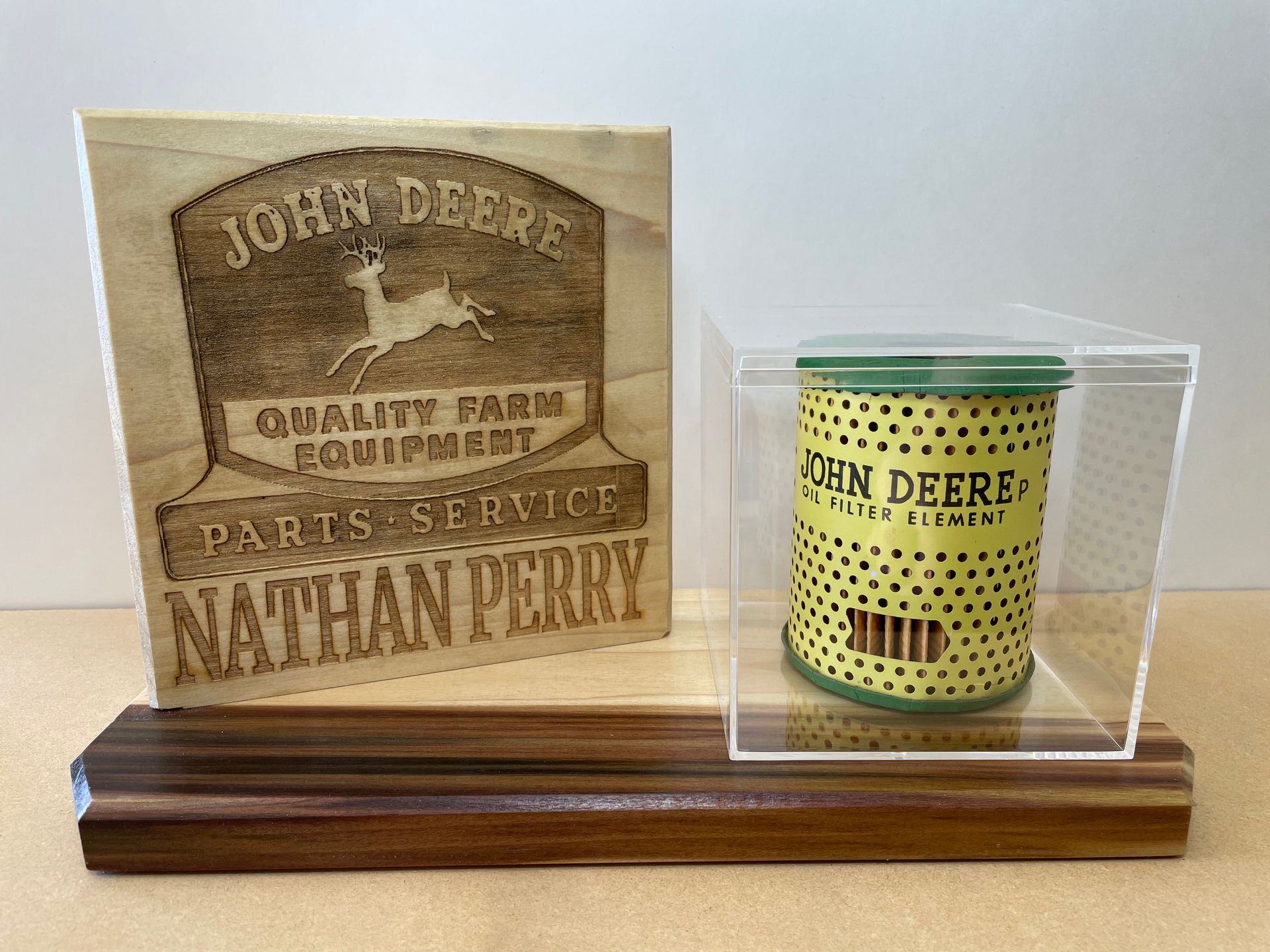 A john deere parts service nathan perry plaque and a john deere oil filter in a display case.