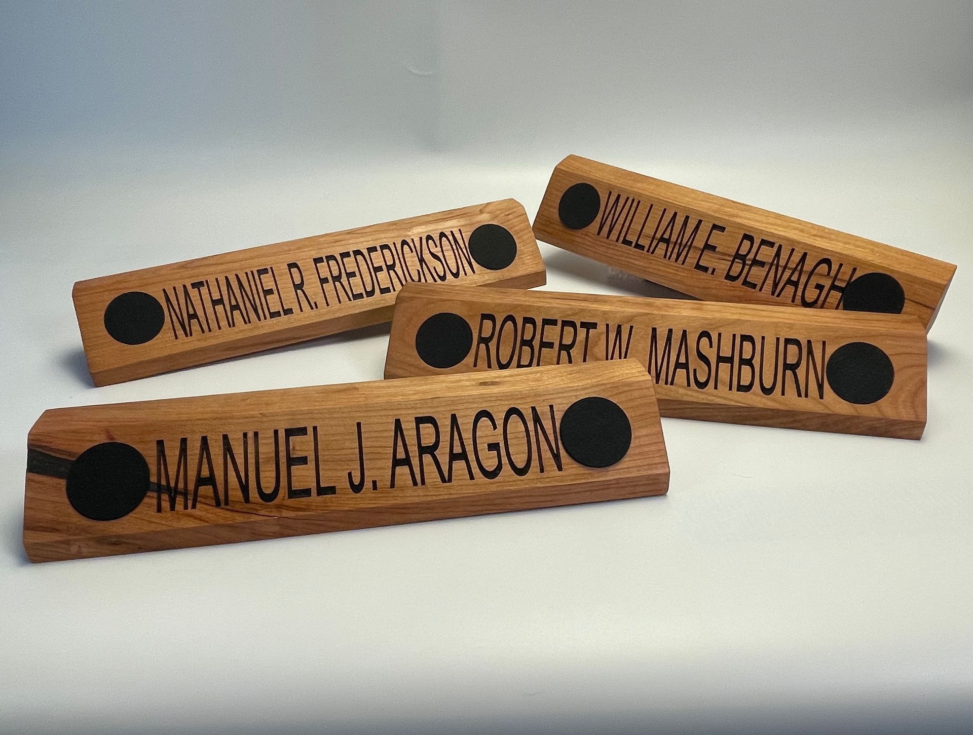 Four wooden name plates with the names manuel j. aragon robertin mashburn and williame benage
