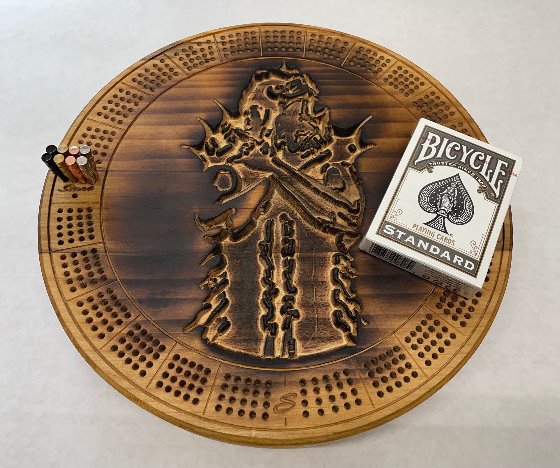 A bicycle standard playing card is sitting on top of a wooden cribbage board.