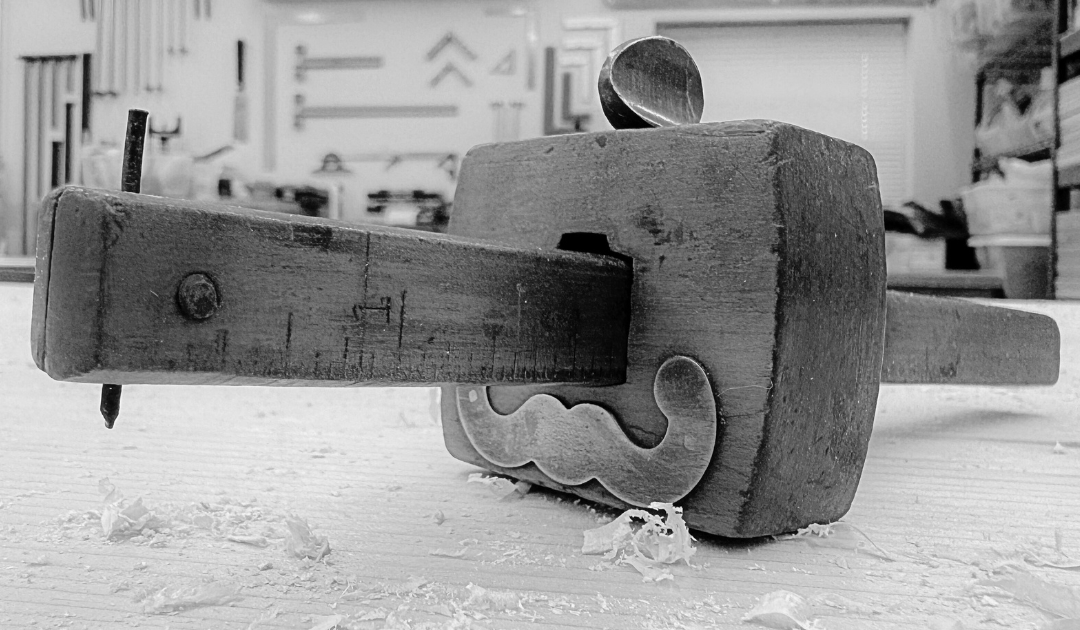 A black and white photo of a wooden tool on a table.