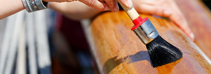 A person is painting a piece of wood with a brush.