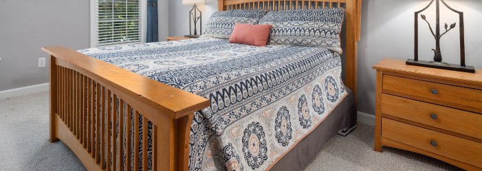 A bedroom with a bed , nightstand , and dresser.