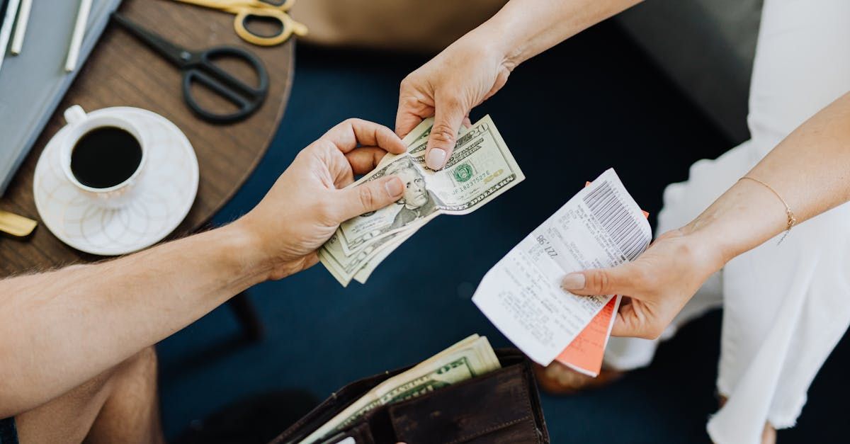 A man and a woman are sitting at a table holding money and receipts.