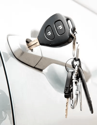 A Bunch of Car Keys Are Hanging from The Door Handle of A Car — Coffs City Lockmart Pty Ltd in North Boambee Valley, NSW
