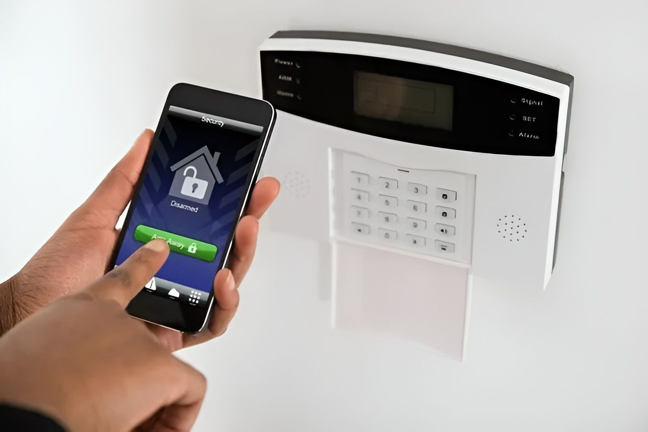 A phone is being held up to security system pad on wall — Coffs City Lockmart Pty Ltd in North Boambee Valley, NSW