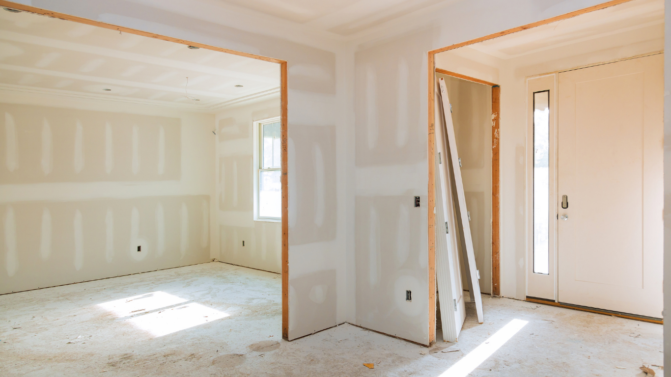 Interior view of a room under construction, with drywall, wooden framing, and a door.