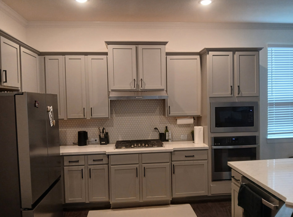 Gray kitchen with cabinets, stainless steel appliances, and white countertops.