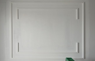 White wall with rectangular trim and ladder below.