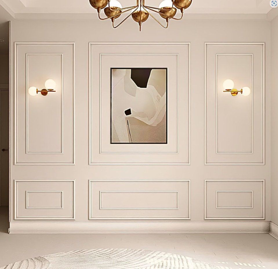 Cream-colored wall with decorative molding, art, sconces, and a chandelier.