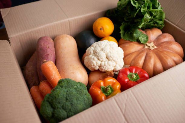 A cardboard box filled with a variety of vegetables.