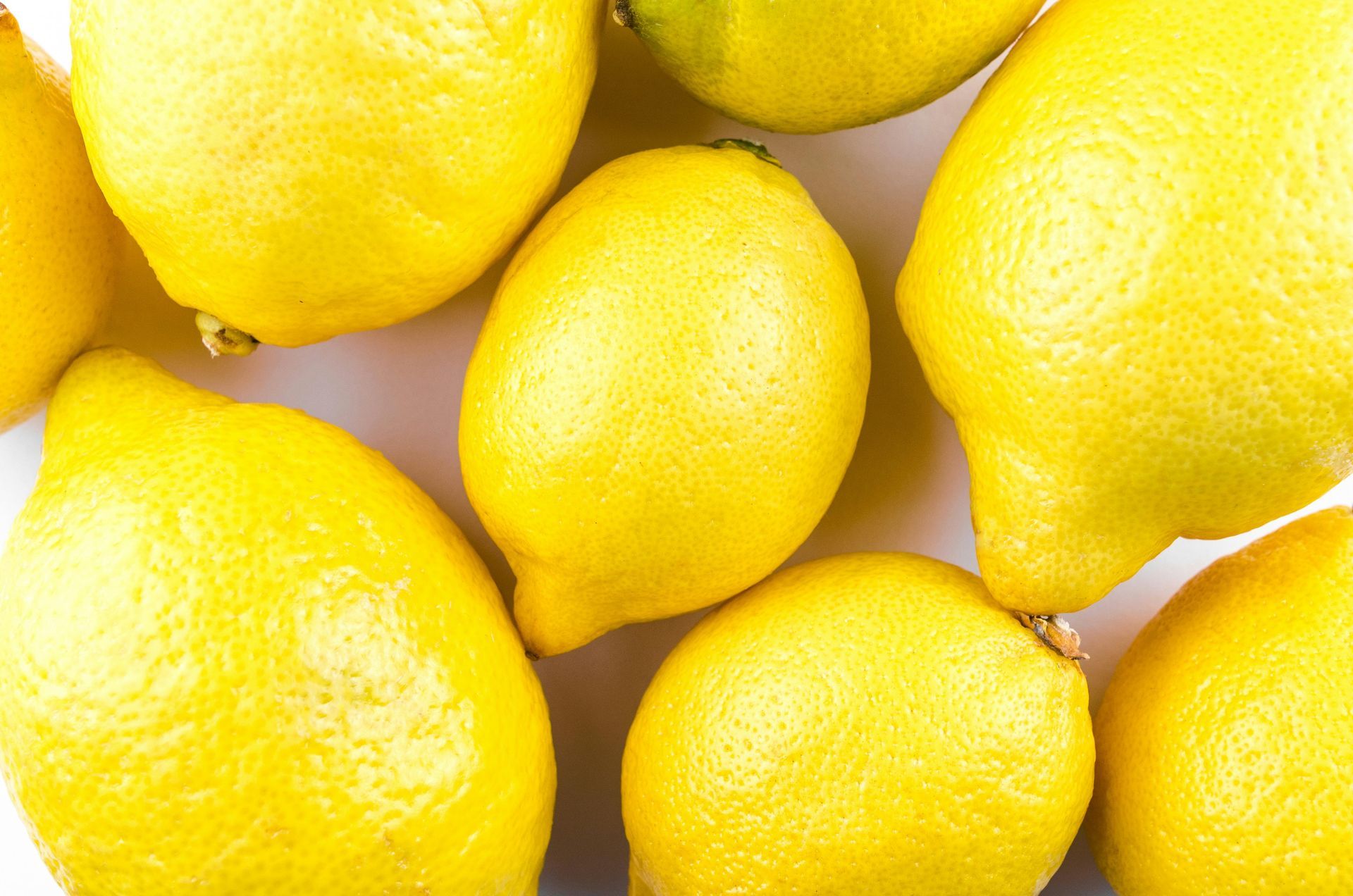 A bunch of lemons are sitting on top of each other on a white surface.
