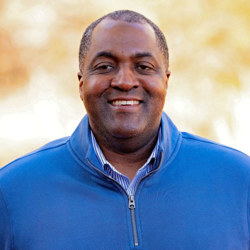 A man in a blue sweater is smiling for the camera.