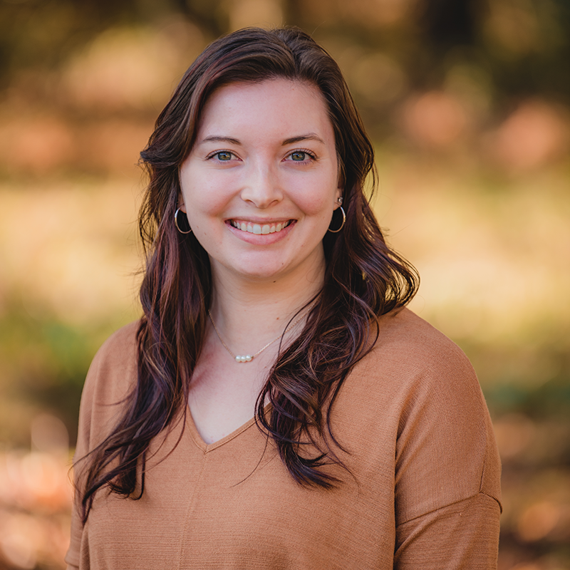 A woman in a brown sweater is smiling for the camera.