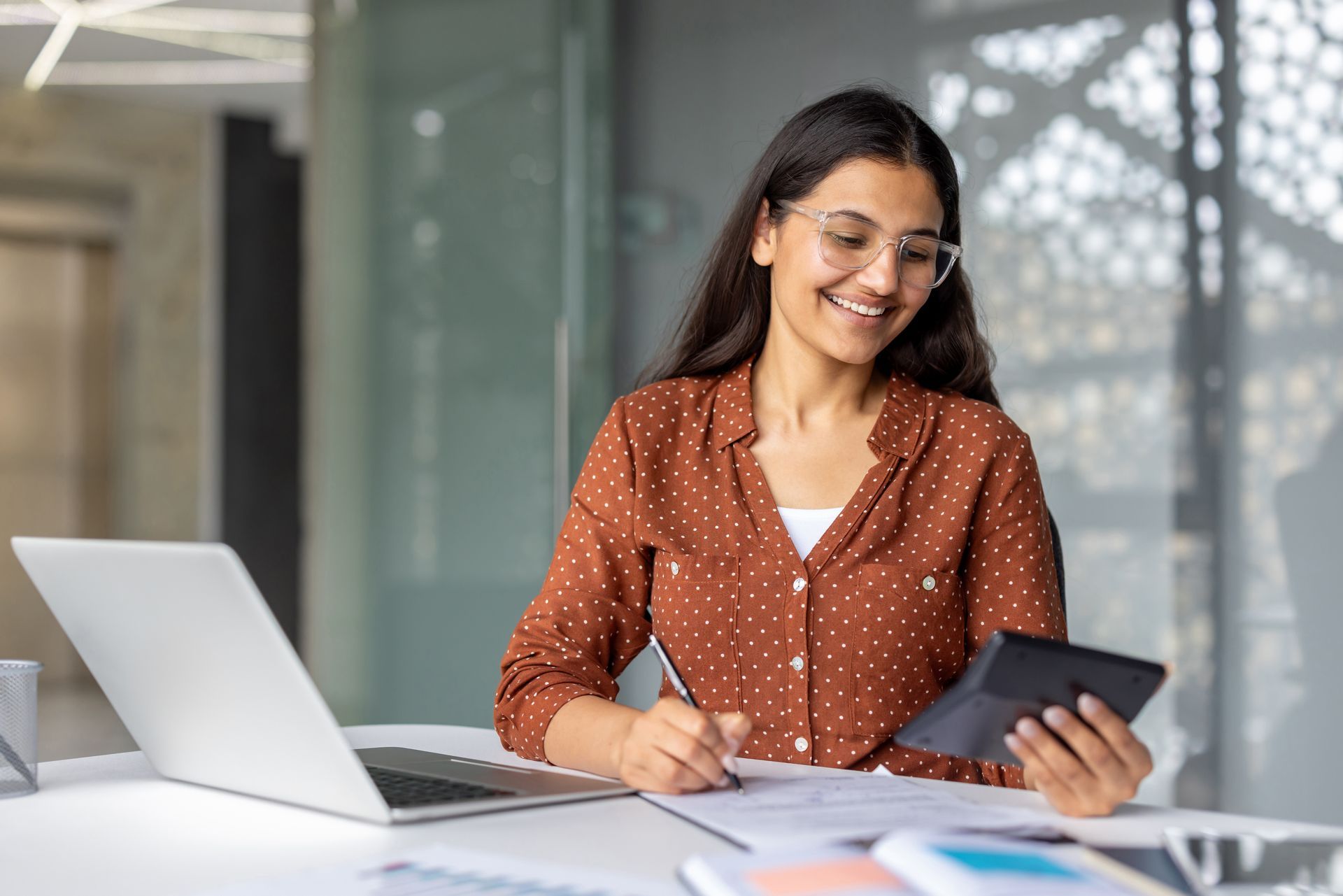 A professional business accountant working on financial reports with a calculator and laptop.