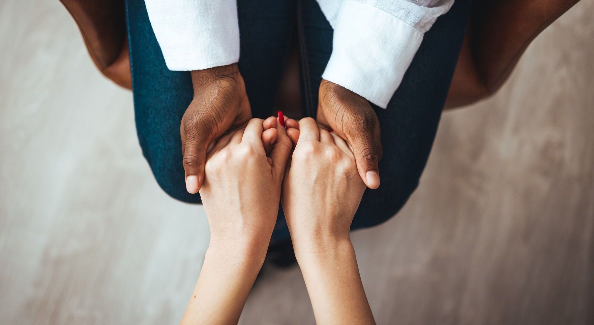 A man and a woman are holding hands while sitting on the floor.