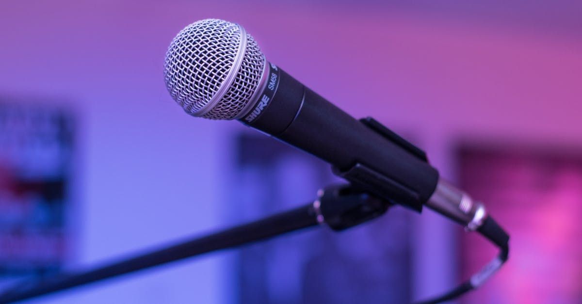 A microphone is sitting on a stand in front of a purple background.