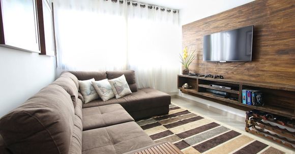 A living room with a couch , rug , television and wooden wall.