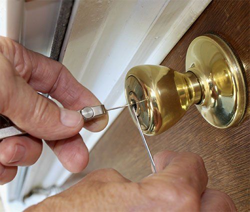 A person is using a key to open a door knob.