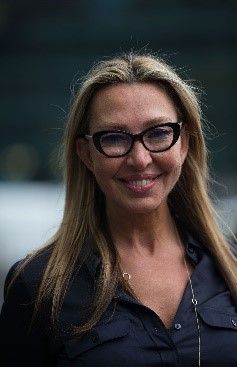 A woman wearing glasses and a black shirt is smiling for the camera.