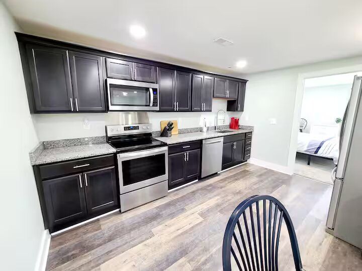 A kitchen with stainless steel appliances and black cabinets.