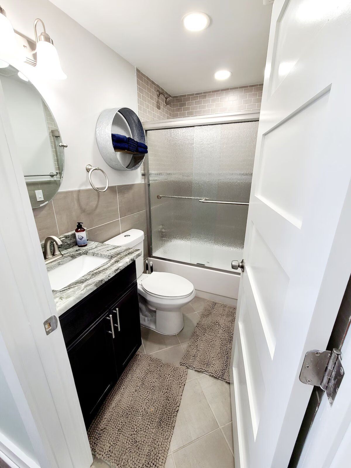 A bathroom with a toilet , sink , mirror and shower.