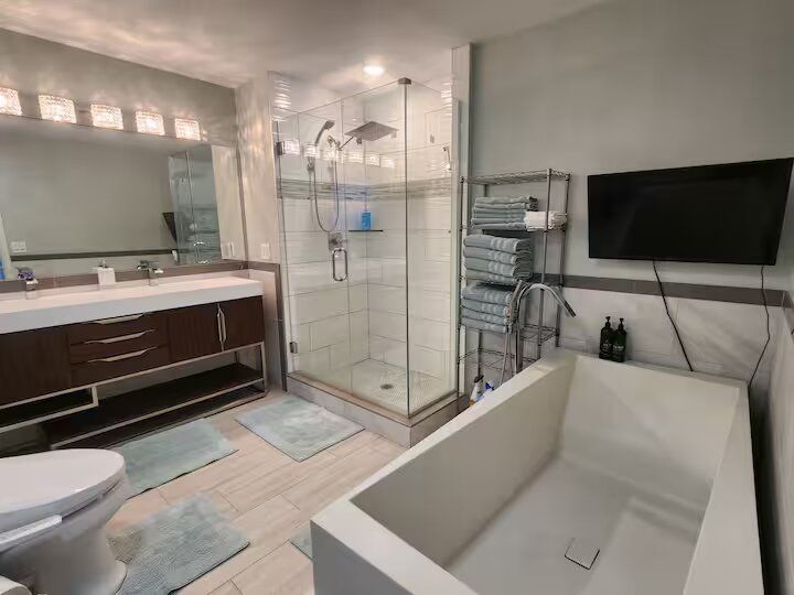 A bathroom with a tub , toilet , sink and shower.
