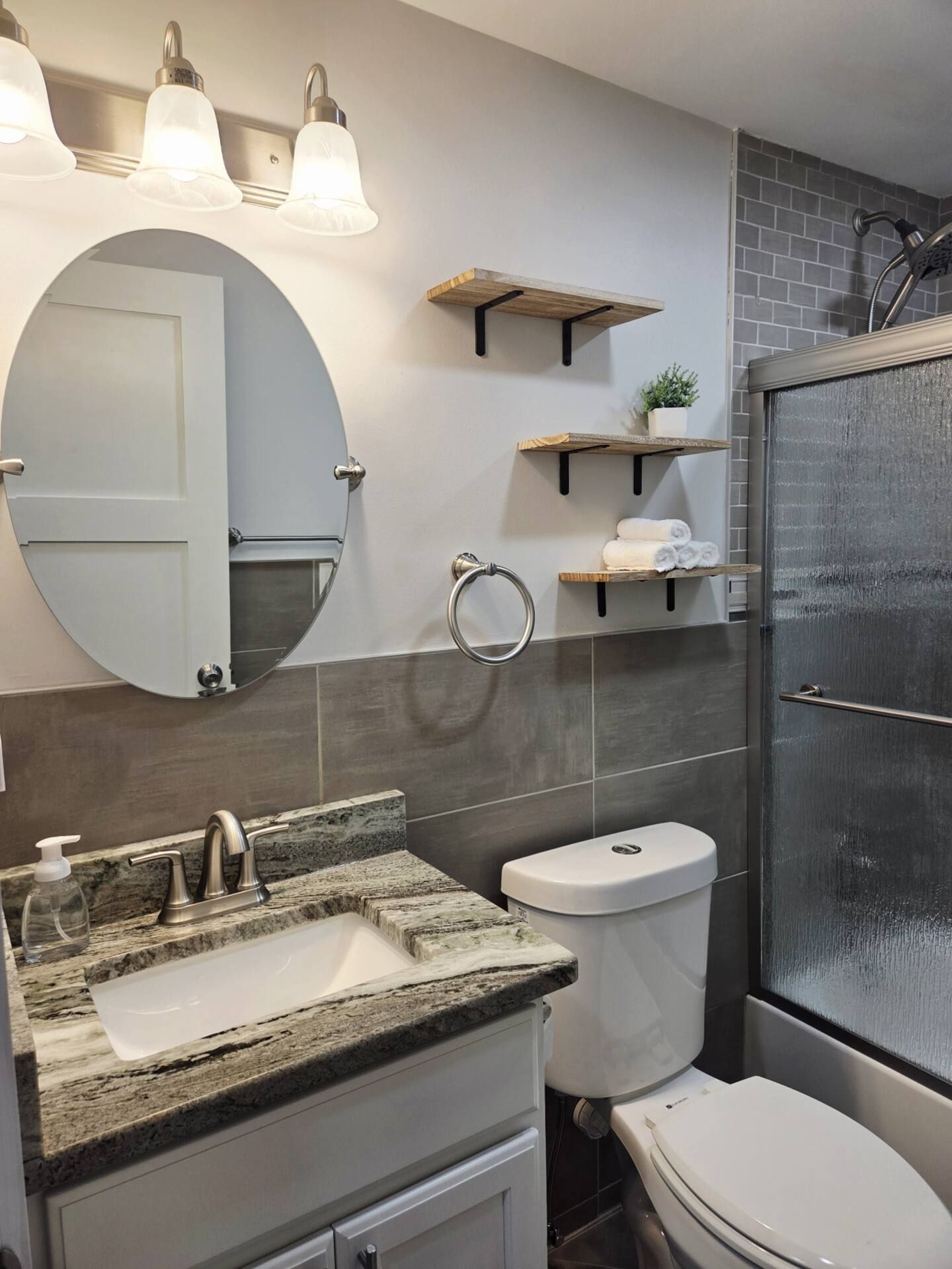 A bathroom with a toilet , sink , mirror and shower.