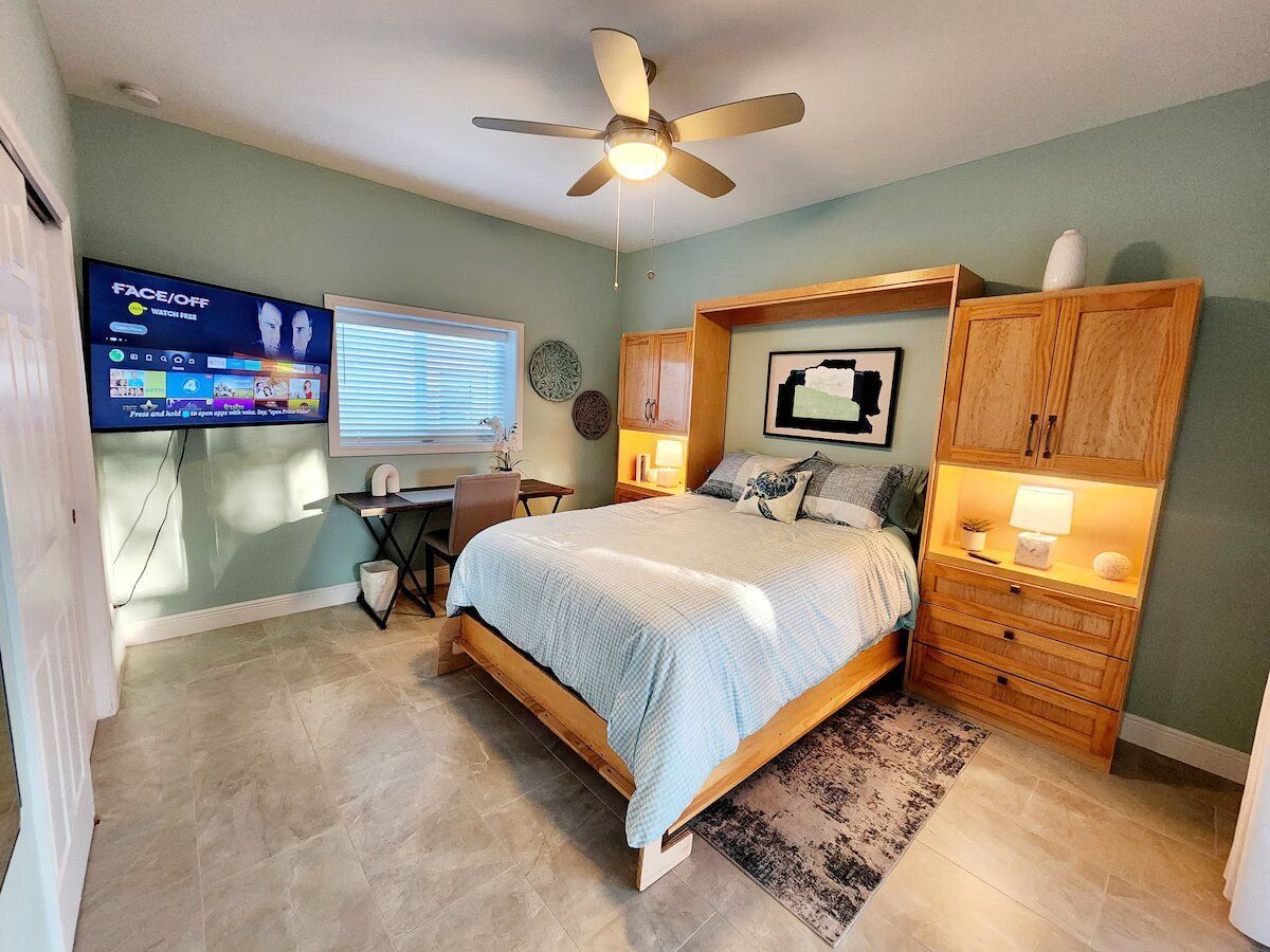 A bedroom with a king size bed , a flat screen tv , and a ceiling fan.