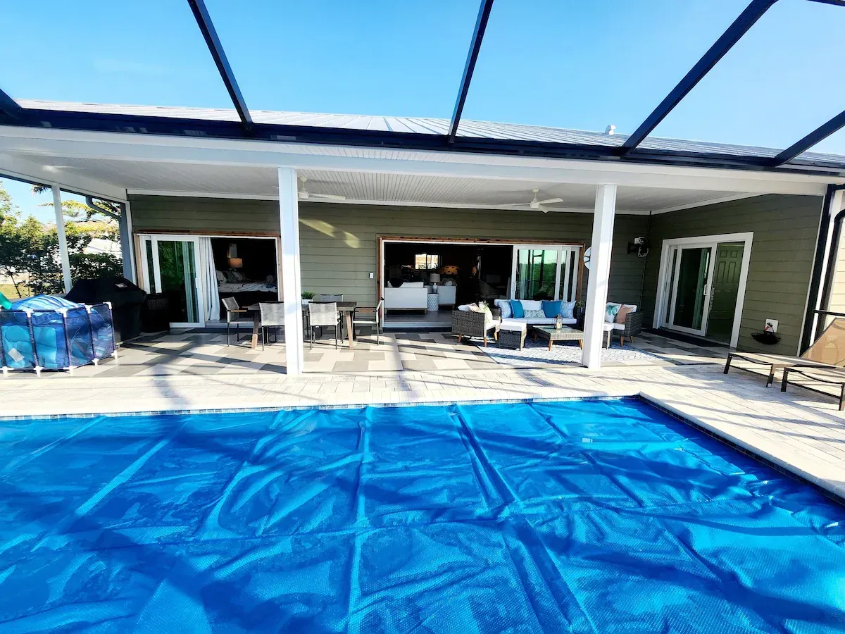 There is a large swimming pool in the backyard of a house.