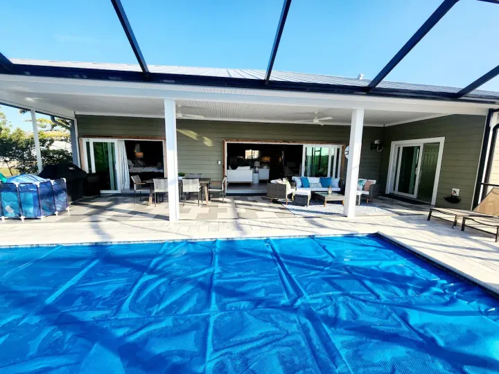 There is a large swimming pool in the backyard of a house.